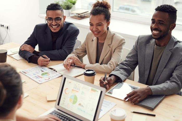Three coworkers laughing together at a meeting table